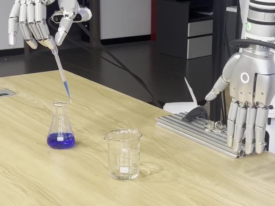 The robotic hand holding a pipette it has just lifted out of the flask